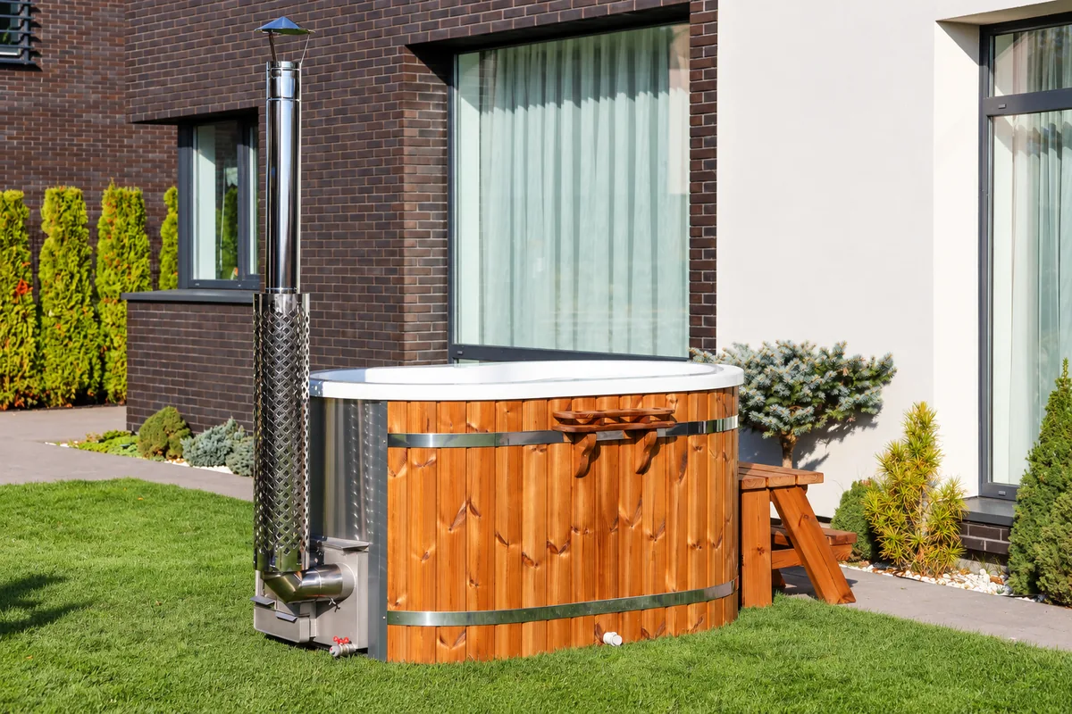 Ofuro Hot Tub mit Holzverkleidung und Holzofen vor einem modernen Haus