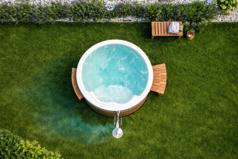 Rundes Badefass mit weißer Acrylwanne, Holzverkleidung und Holzofen im Garten